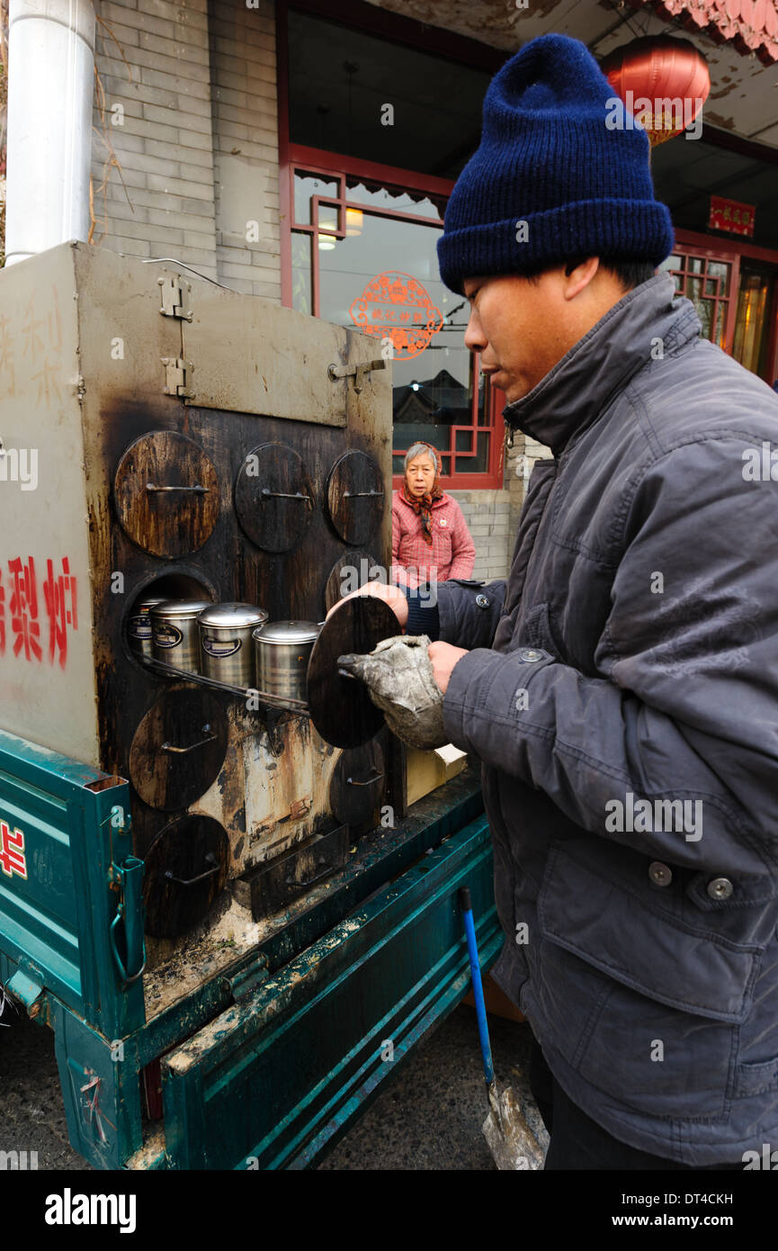 Man bereitet einen warmen Snack in einem mobilen Ofen. Peking, China Stockfoto