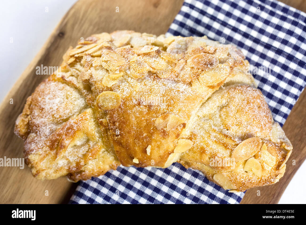 Mandel-Croissant. Einzelne halbmondförmige Blätterteig auf einem Holzbrett. Stockfoto