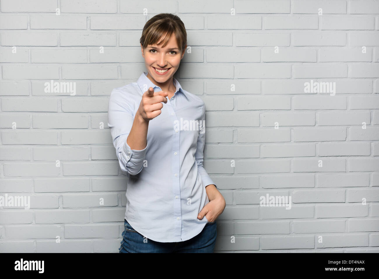 Weibliche casual glücklichen Studio Punkt Finger grau isoliert Hintergrund Stockfoto