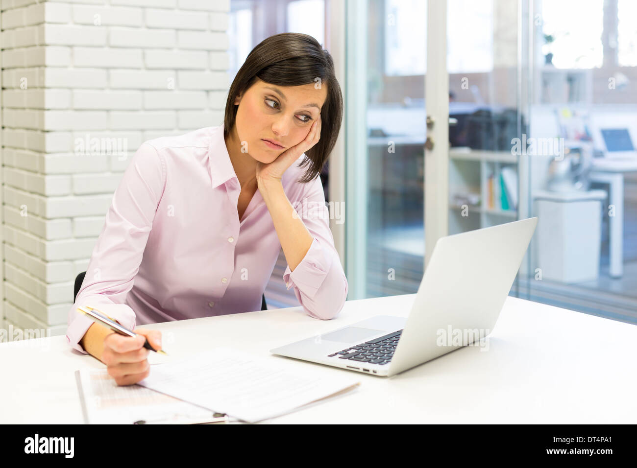 Müde Geschäftsfrau am Schreibtisch arbeiten mit Papier und computer Stockfoto