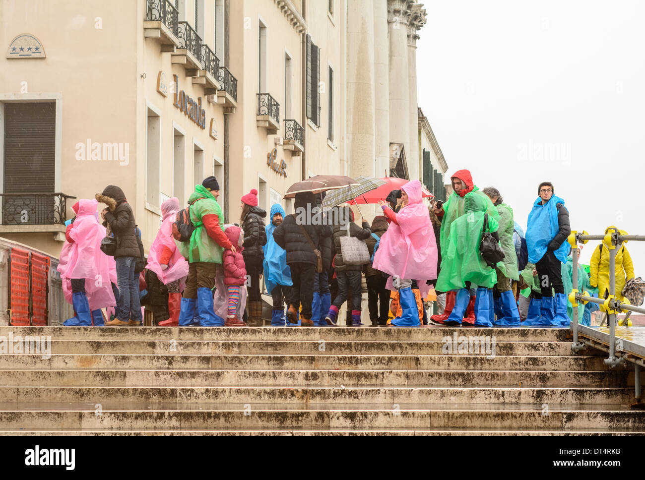 Venedig, Italien. Touristen und Kinder bei nassem Wetter Kleidung und Regen Stiefel, auf einer Brücke im Regen stehen. Stockfoto