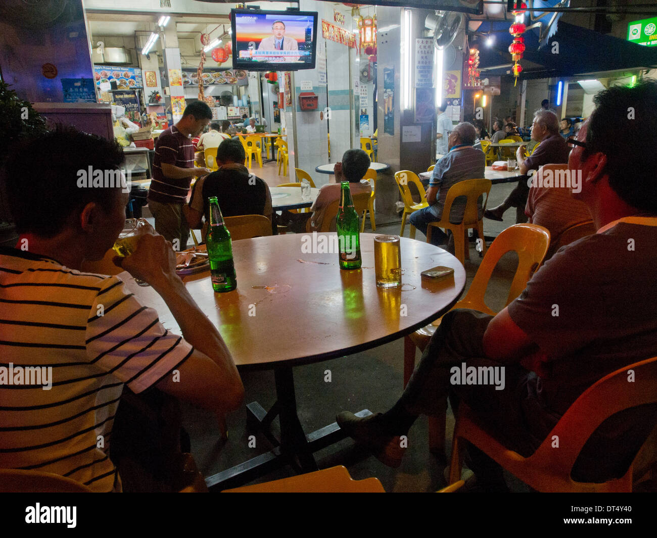 Menschen Essen und trinken während des Fernsehens an Außenbar in Geylang, Red Light District in Singapur Stockfoto