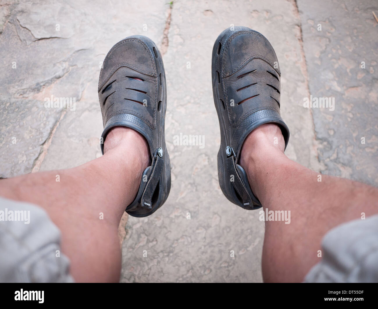 Blick auf abgenutzte, staubigen paar Crocs clogs an den Füßen eines jungen Mannes. Stockfoto