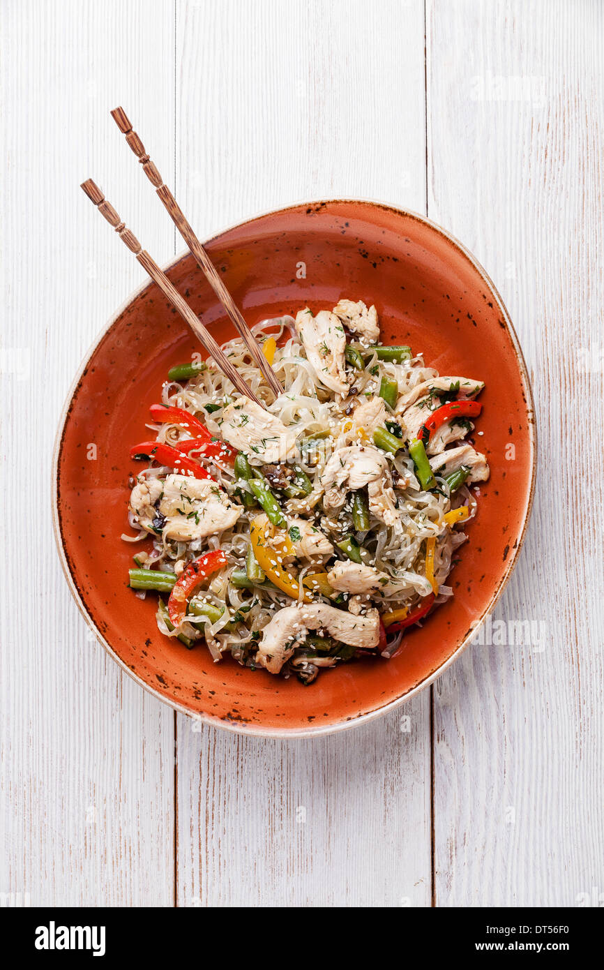 Rühren Sie braten Huhn mit Gemüse und Reisnudeln auf rotem Teller Stockfoto