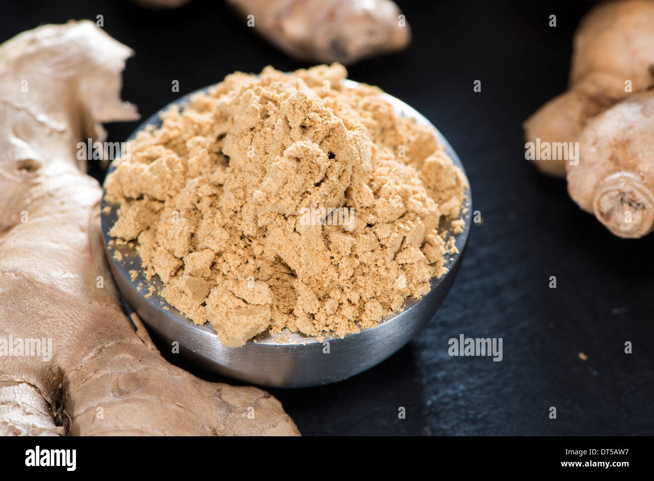 Kleine Schale mit Ginger Powder auf dunklem Hintergrund Stockfoto