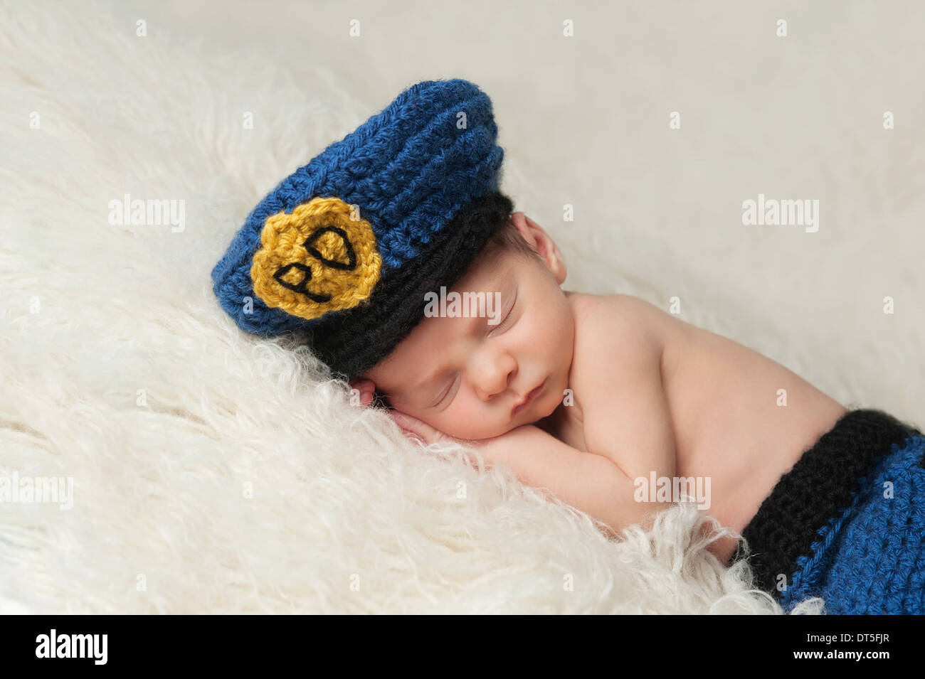 Schlafen 12 Tage altes neugeborenes Baby Boy trug ein blau und Gold gehäkelt Polizei Offizier Hut. Stockfoto