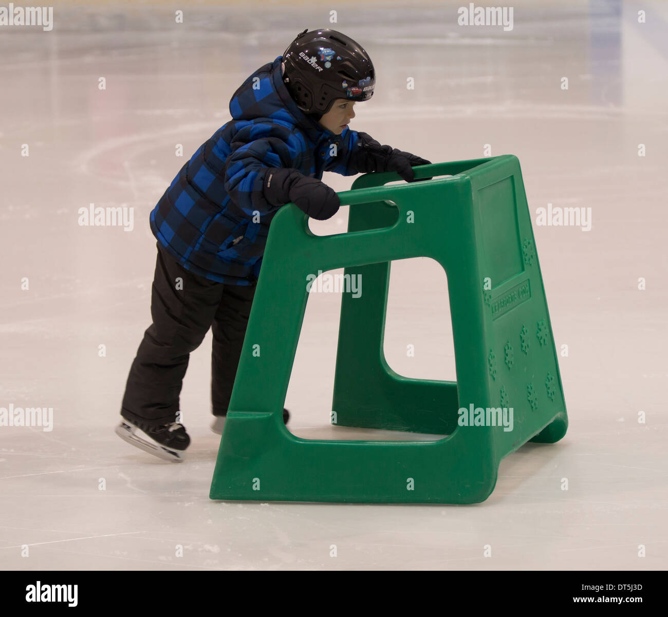 Kleiner Junge mit Hilfe auf dem Eis Schlittschuh laufen lernen Stockfoto