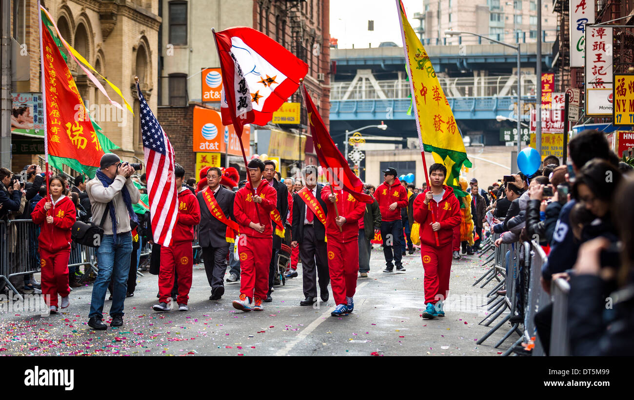 Lunar New Year Festival feierte in Manhattans Chinatown. Junge Männer, gekleidet in roten Kostümen tragen Fahnen. Stockfoto