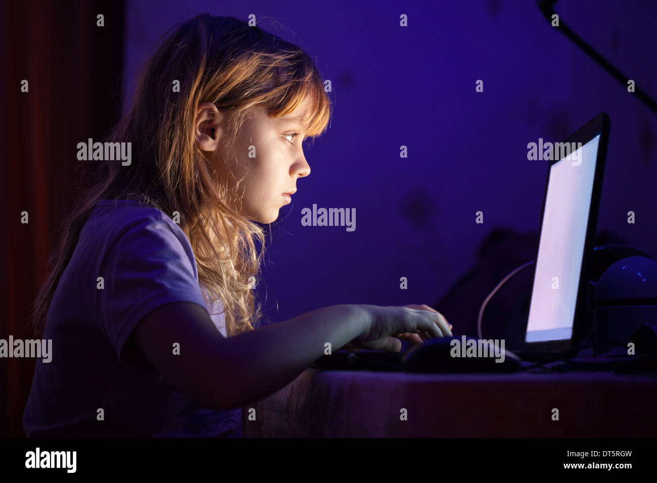 Kleine blonde Mädchen Nachtarbeit auf Laptop im dunklen Raum Stockfoto