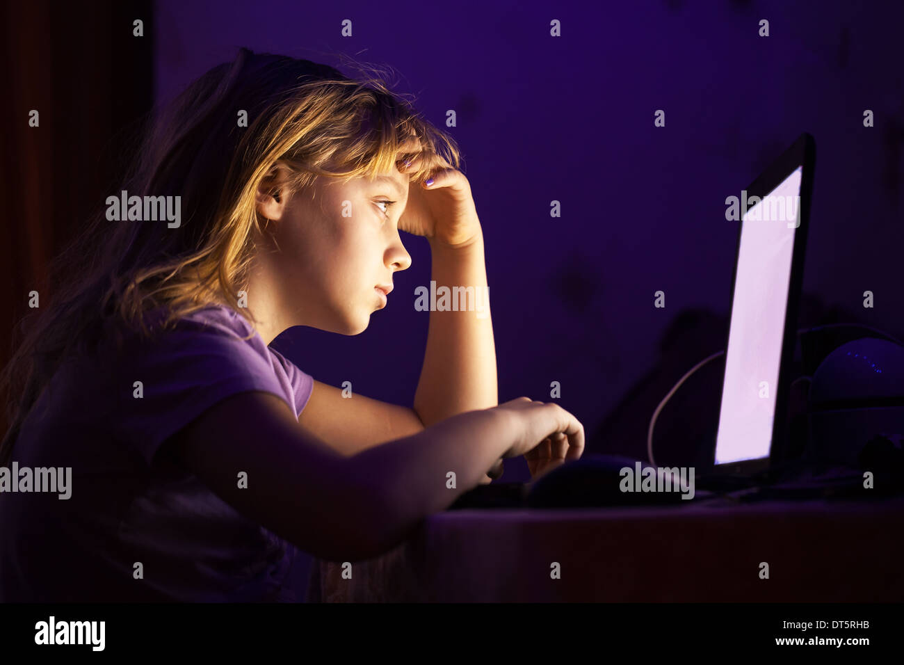 Wenig kaukasische Mädchen arbeiten am Laptop im dunklen Raum in der Nacht Stockfoto