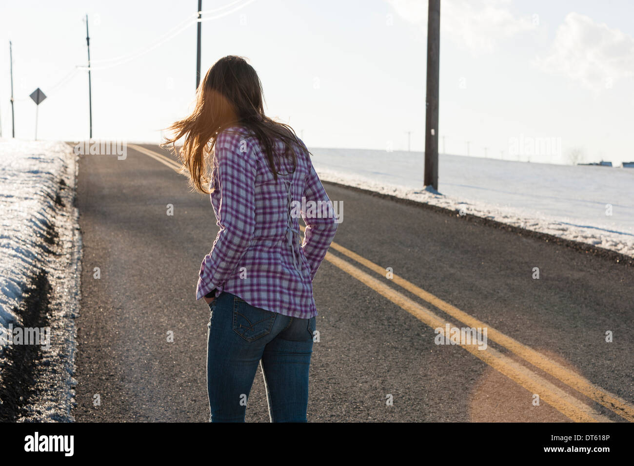 Junge Frau zu Fuß entfernten Straße im winter Stockfoto