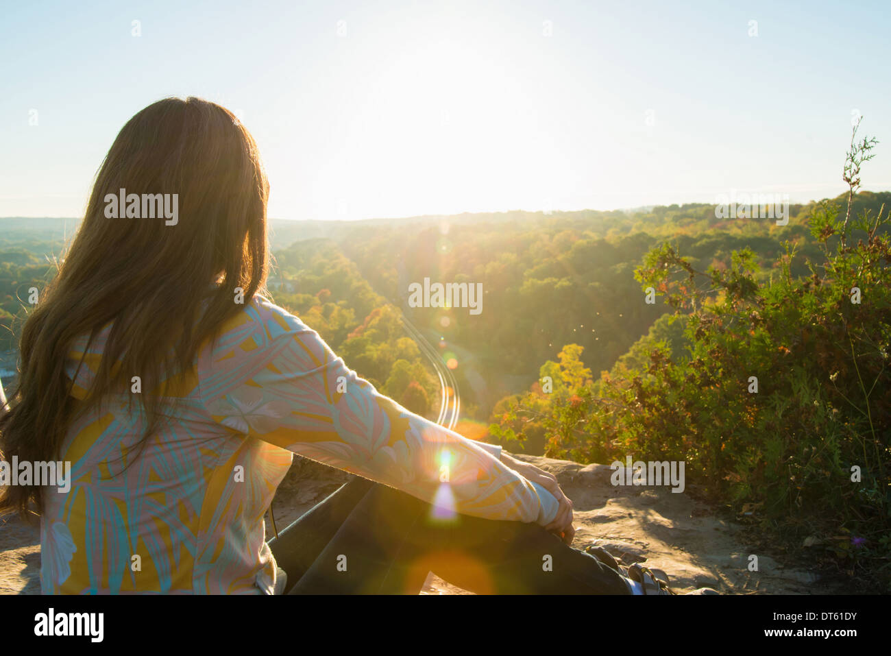 Mitte Erwachsene Frau sitzen auf hohen Felsen Sonnenaufgang zu beobachten Stockfoto