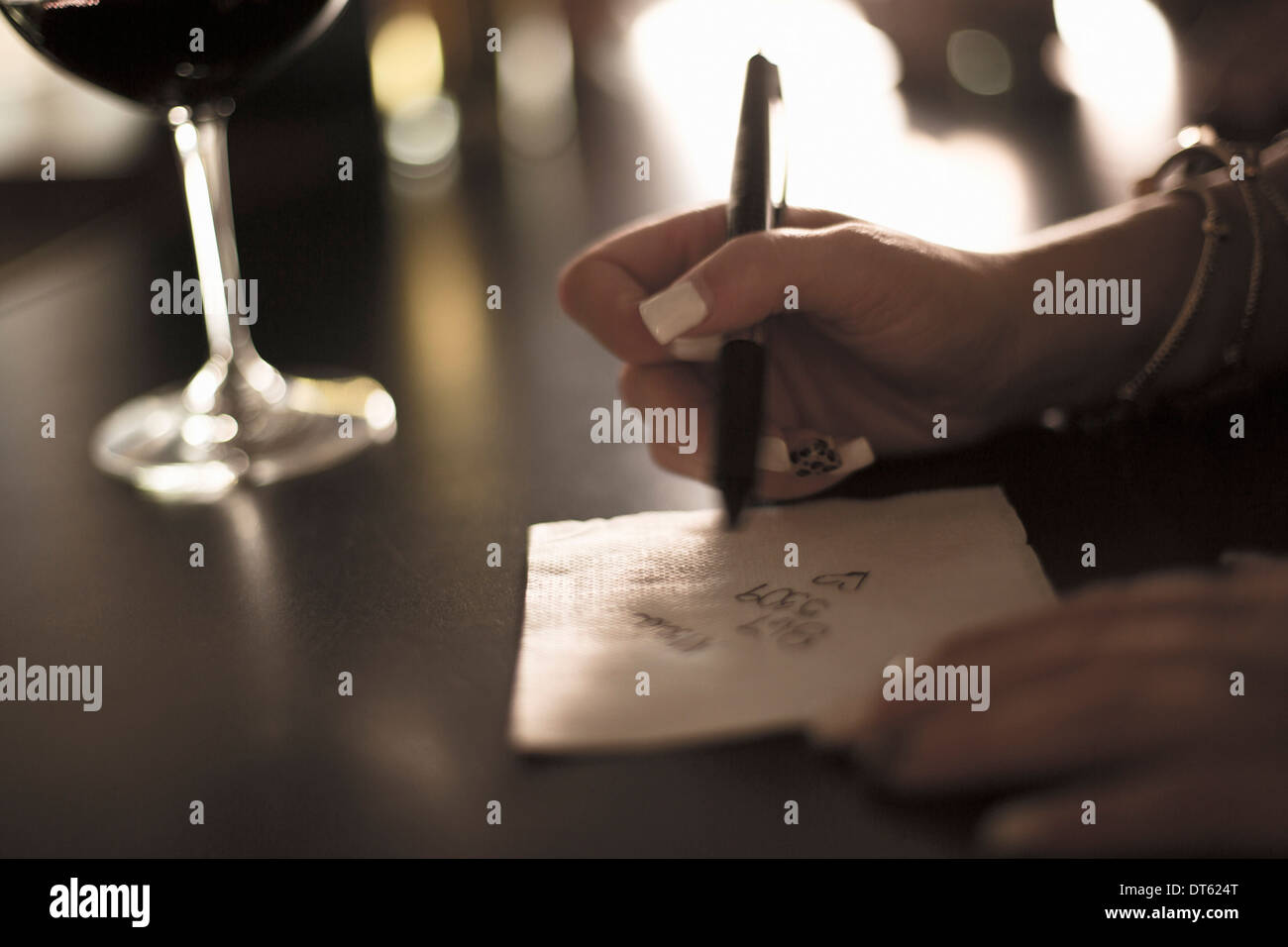 Nahaufnahme der jungen Frau schreibt ihre Telefonnummer auf einer Serviette in der Bar Stockfoto