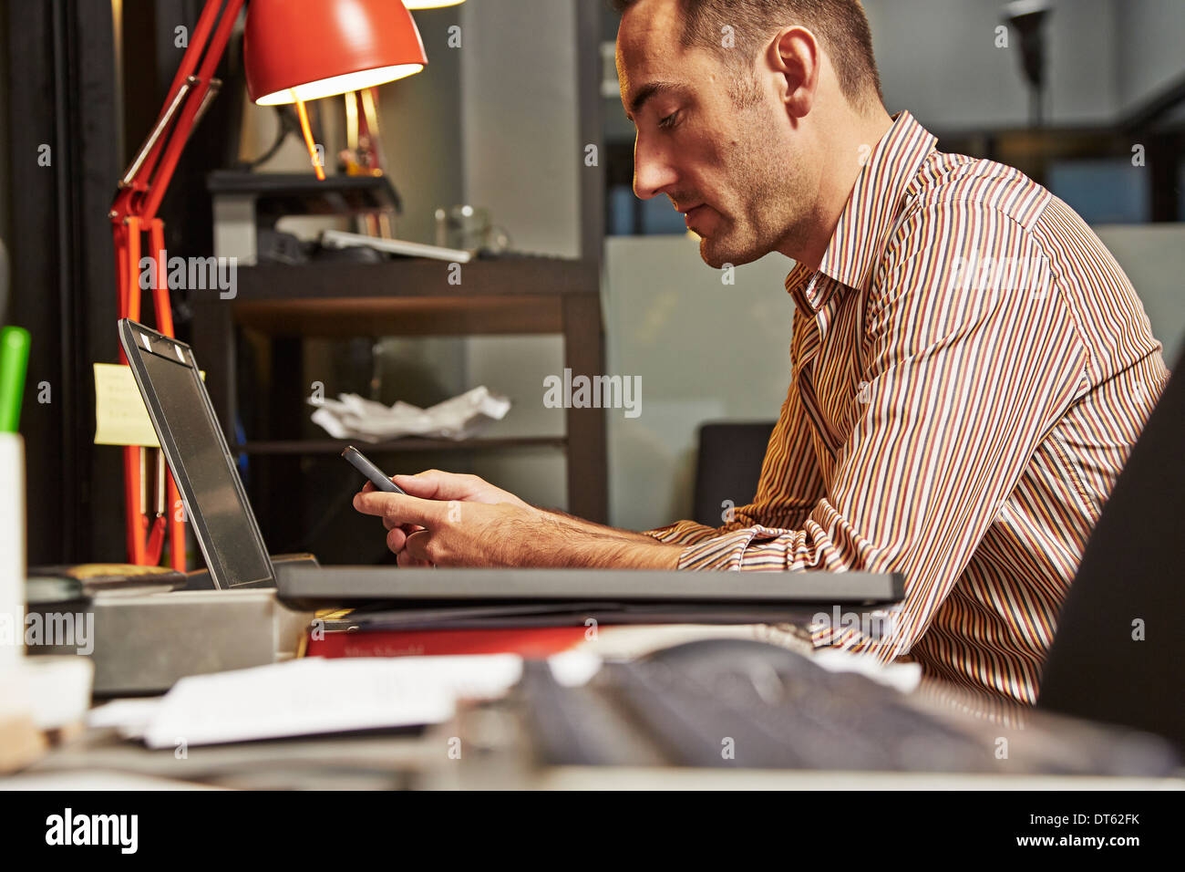 Geschäftsmann am Schreibtisch mit Handy Stockfoto