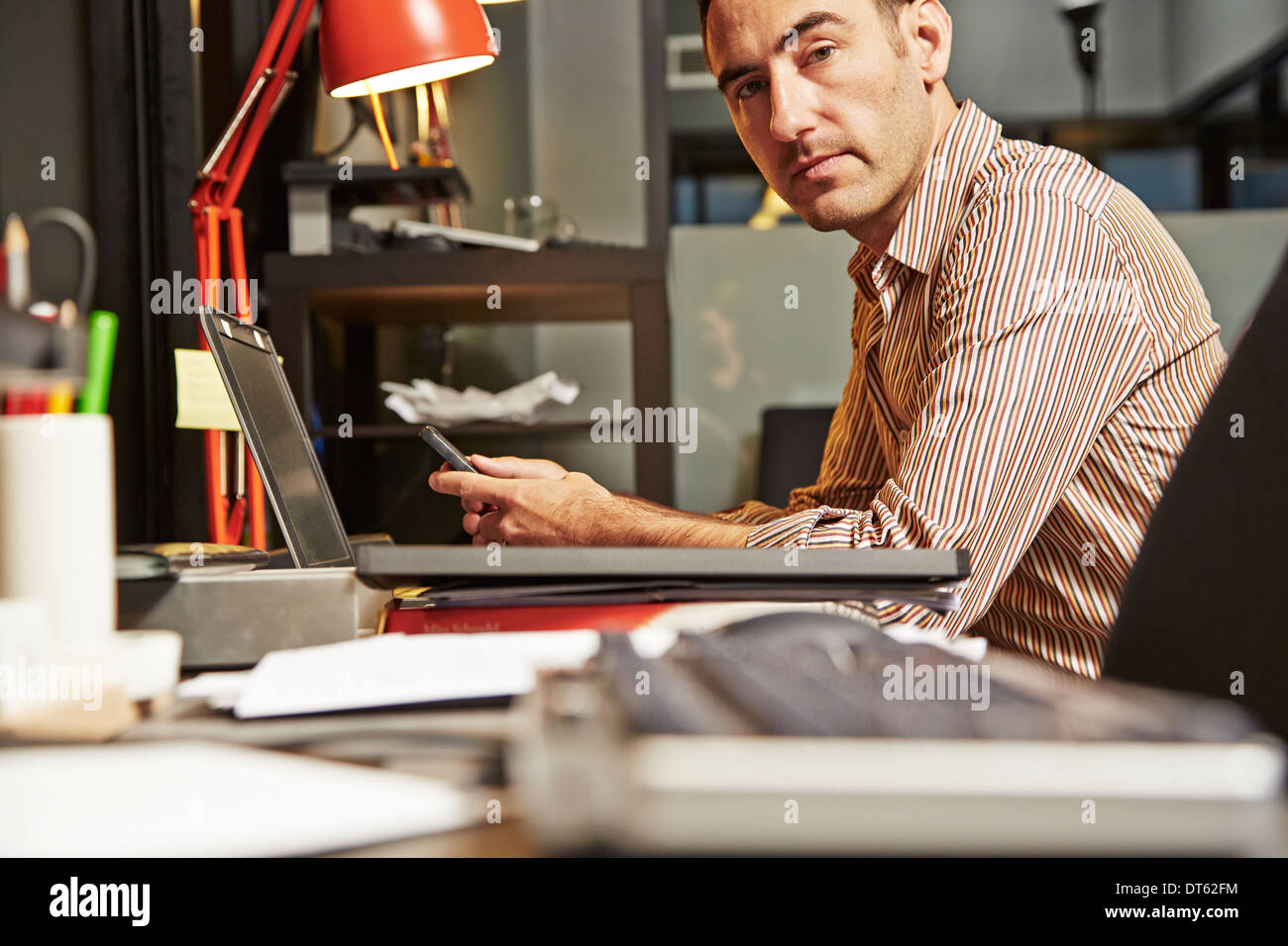 Geschäftsmann am Schreibtisch mit Handy Stockfoto