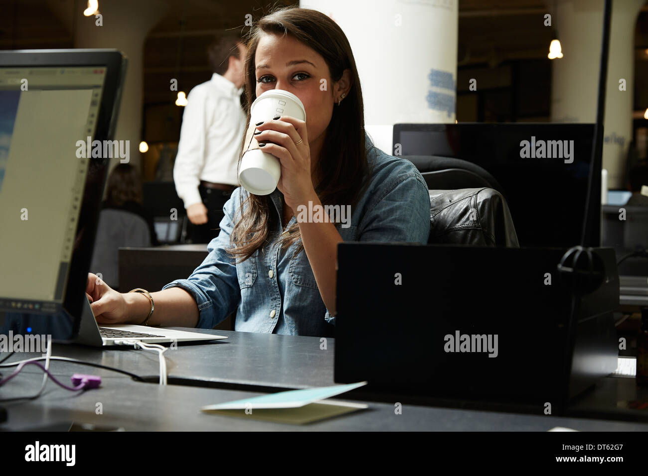 Junge Frau trinkt Kaffee im Büro Stockfoto