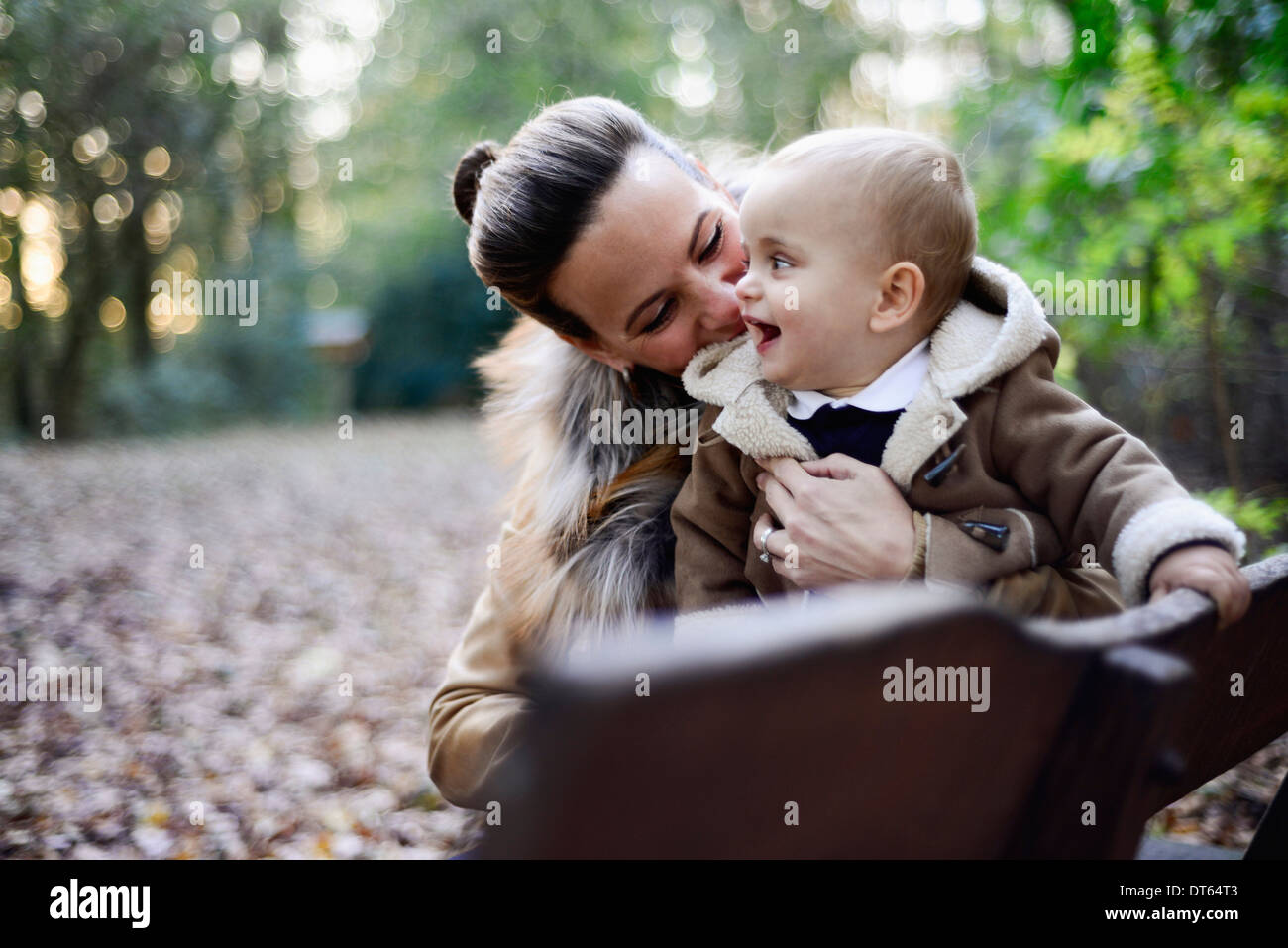 Mutter Betrieb männliche Kleinkind auf Wald Parkbank Stockfoto