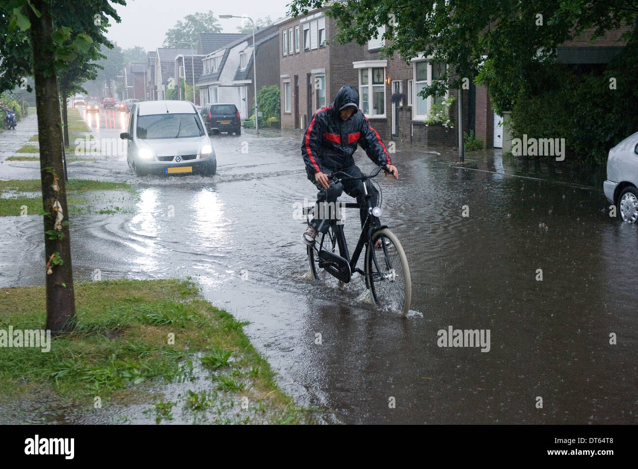 Ein Mann auf einem Fahrrad reitet durch das Wasser nach einem Regenguss Stockfoto