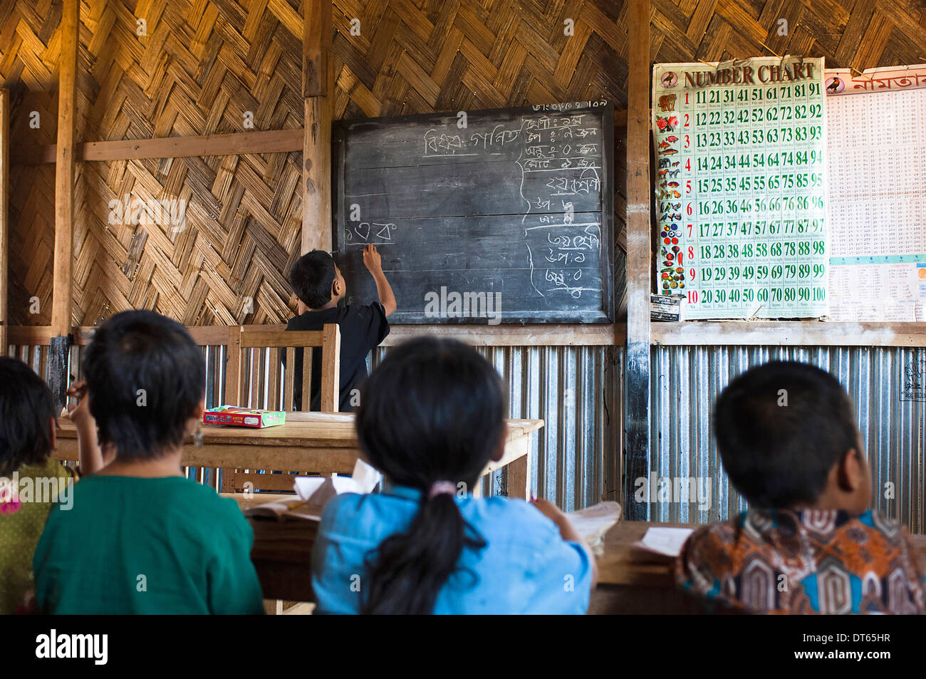 Bangladesch, Südasien, Chittagong, Boy schreiben aus Bangladesch an der Tafel in einem UNO unterstützt ländliche Grundschule Unterricht. Stockfoto