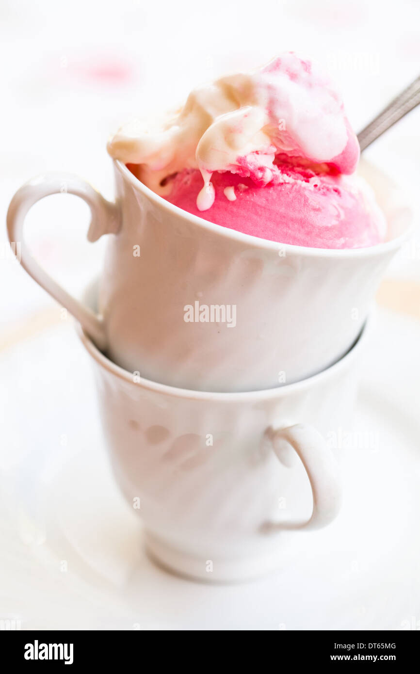 Nahaufnahme der Tasse mit Himbeer und Vanille-Eis und Löffel auf hellem Hintergrund Stockfoto