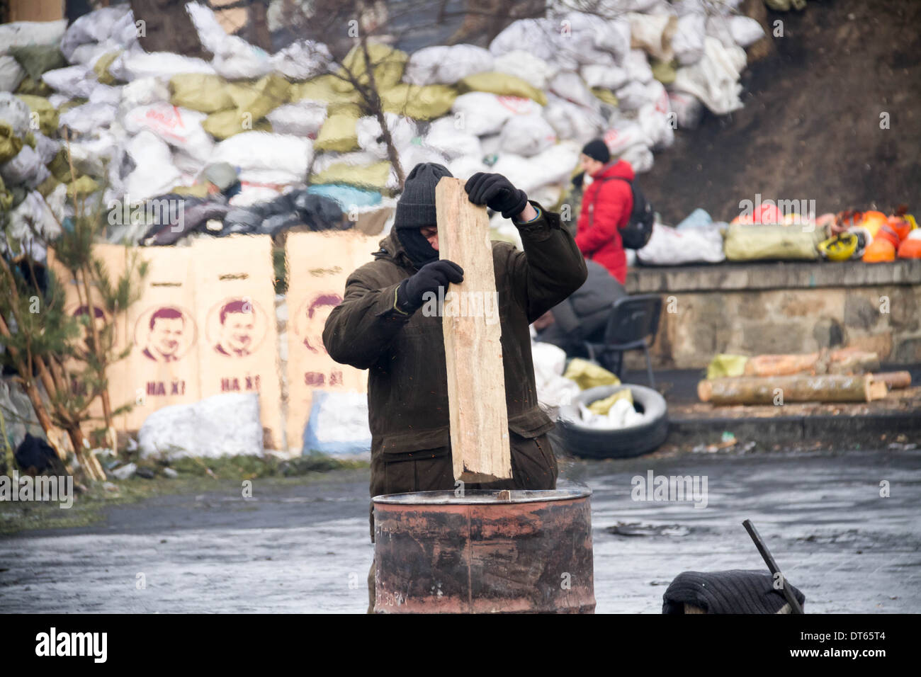 Ein Euromajdan Demonstrant hält warm auf den Barrikaden auf Gruschevsky Straße in Kiew, Ukraine. Regierung Polizei stehen vor uns. Stockfoto