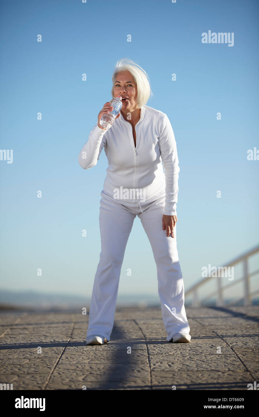 Reife Frau Trinkwasser auf Spaziergang Stockfoto