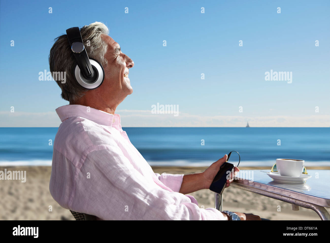 Senior woman Musikhören mit Kopfhörer am Strand Stockfoto