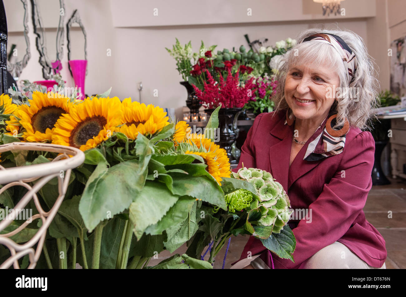 Ältere Frau betrachten Sonnenblumen im Blumenladen Stockfoto