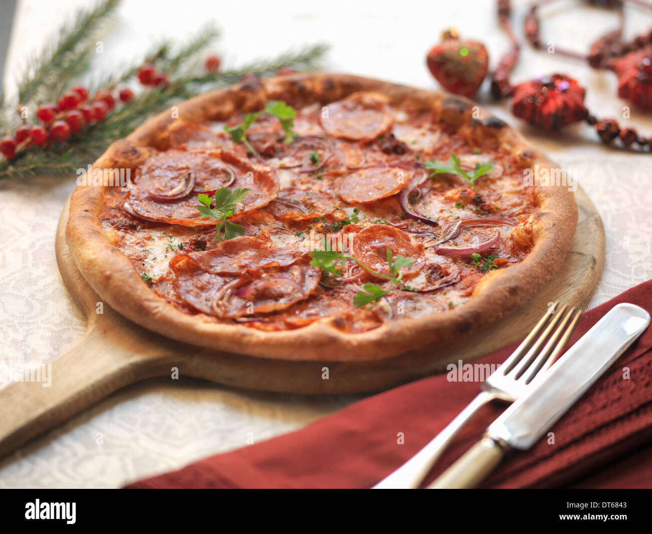 Hausgemachte Pizza mit würziger Salami, heiße kalabrische Wurst, rote Zwiebel und Mozarella Käse mit festlichen Dekorationen Stockfoto