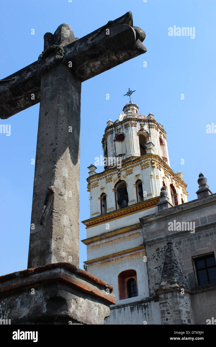 Kreuz im Vordergrund vor der Kirche San Juan (St. John's Church) auf dem Hauptplatz von Coyoacan, Mexiko-Stadt Stockfoto