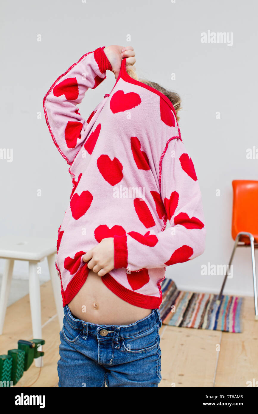 Studioaufnahme des Mädchens versteckt in rotes Herz Pullover Stockfoto