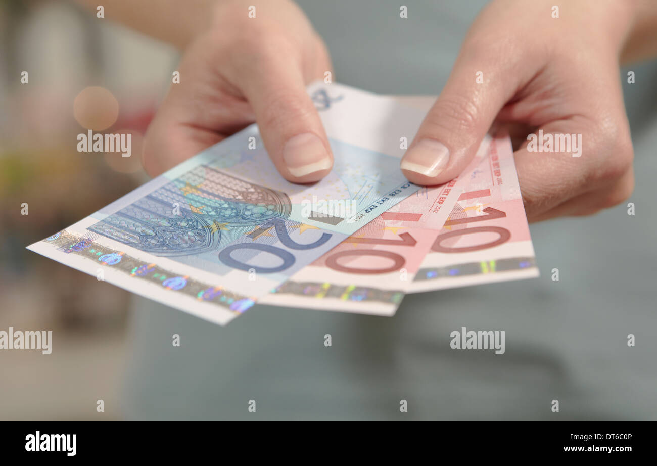 Weibliche Hände halten zehn und zwanzig Euro-Banknoten Stockfoto