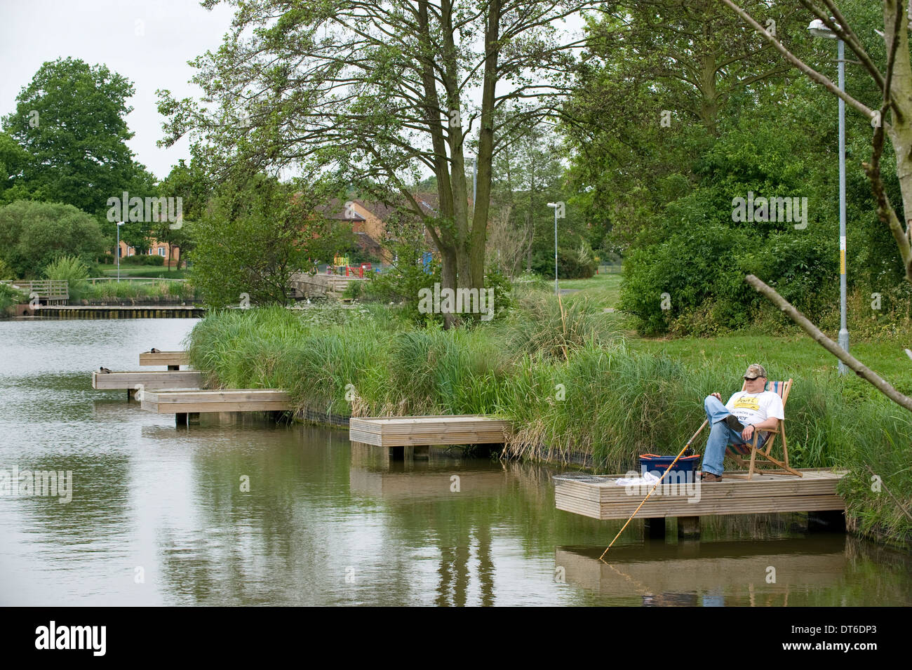 Ein Fischer entspannen und Angeln an einem Teich in innerstädtischer Lage, Redditch, Worcestershire. Stockfoto