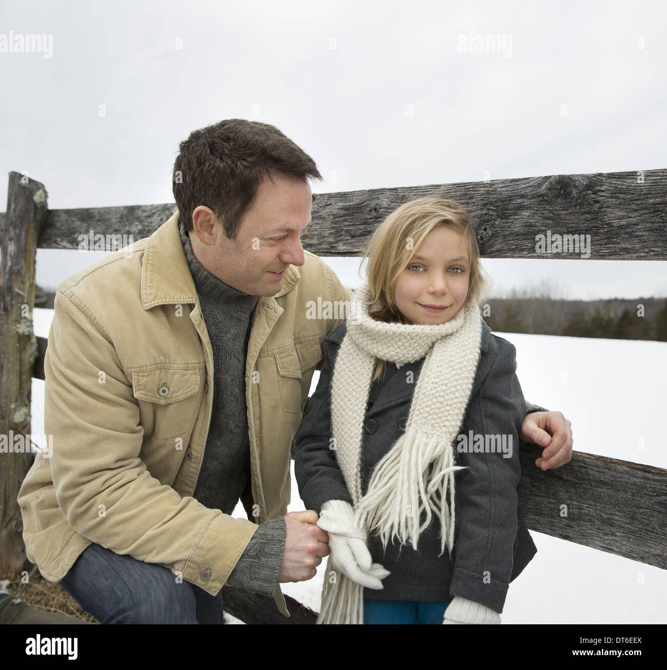 Ein Mann und ein Kind stützte sich auf einen Zaun im Freien.  Ein Bauernhof im Schnee. Stockfoto