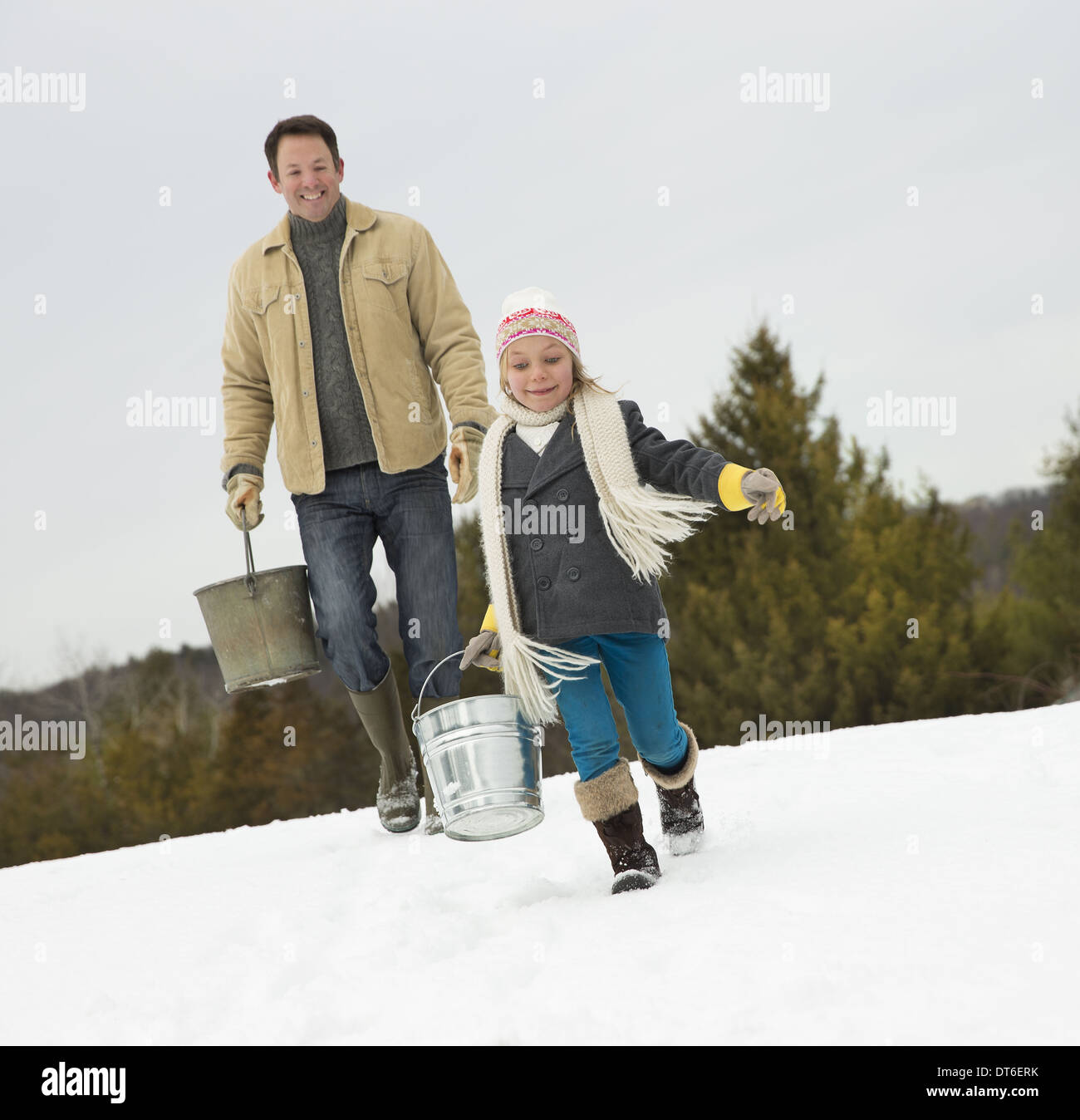 Ein Mann und Kind mit Eimer, durch den Schnee laufen. Stockfoto