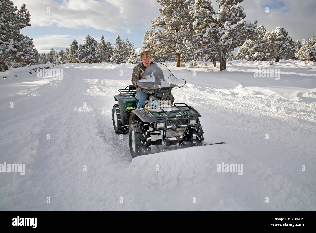 Eine Seniorin Pflüge Schnee mit einem ATV, all-Terrain-Fahrzeug, nach einem großen Schneesturm in Zentral-Oregon. Stockfoto