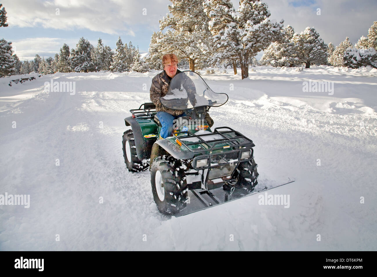 Eine Seniorin Pflüge Schnee mit einem ATV, all-Terrain-Fahrzeug, nach einem großen Schneesturm in Zentral-Oregon. Stockfoto