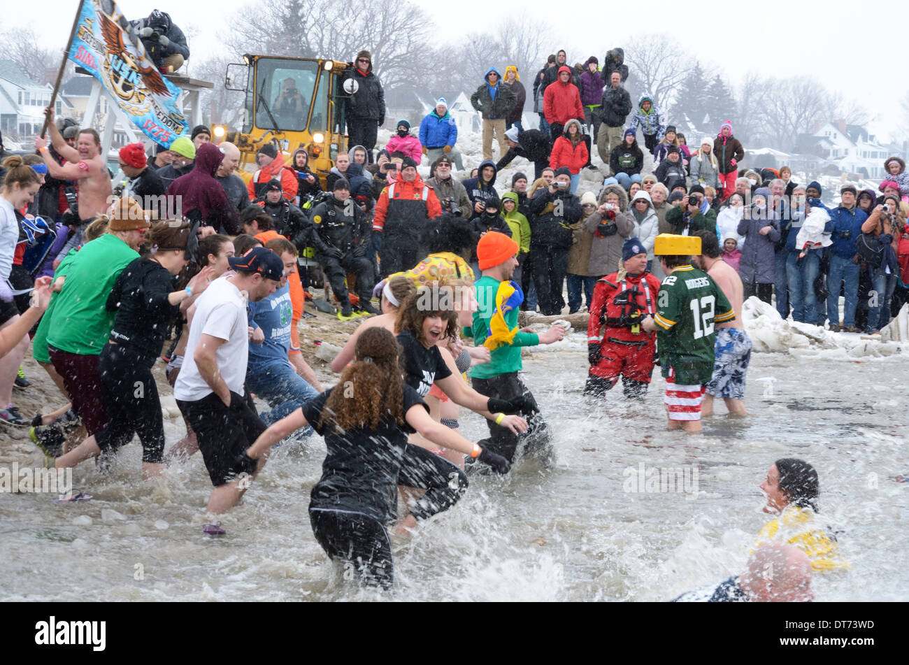 Fans sehen Schwimmer im Eiswasser bei Polar Plunge plantschen. Stockfoto