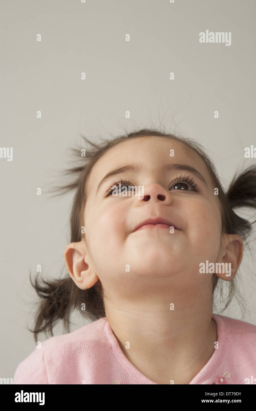 Ein junges Mädchen mit braunen Augen und dunklen Haaren in Trauben. Auf der Suche nach oben mit dem Kopf zurückgeworfen. Stockfoto