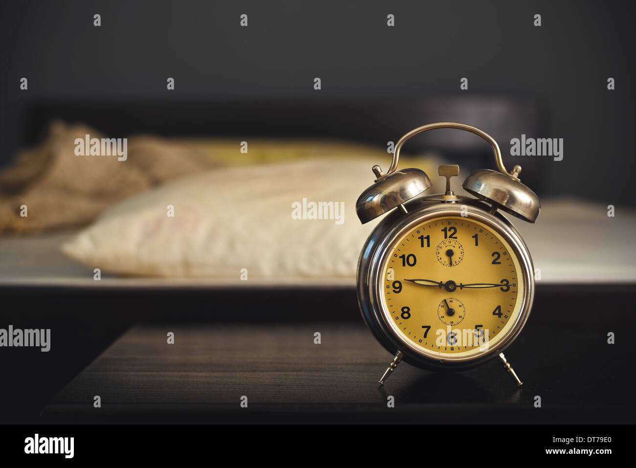 Vintage Wecker im Schlafzimmer auf einem Nachttisch neben dem Bett. Stockfoto