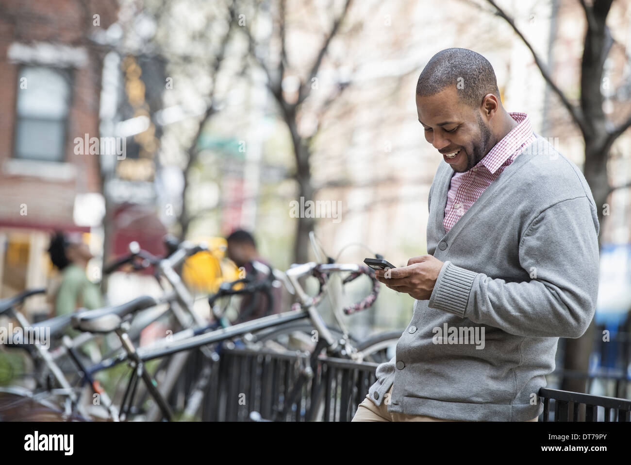 Ein Mann mit seinem Handy. Eine Gruppe von Menschen im Hintergrund. Zyklus-Rack. Stockfoto