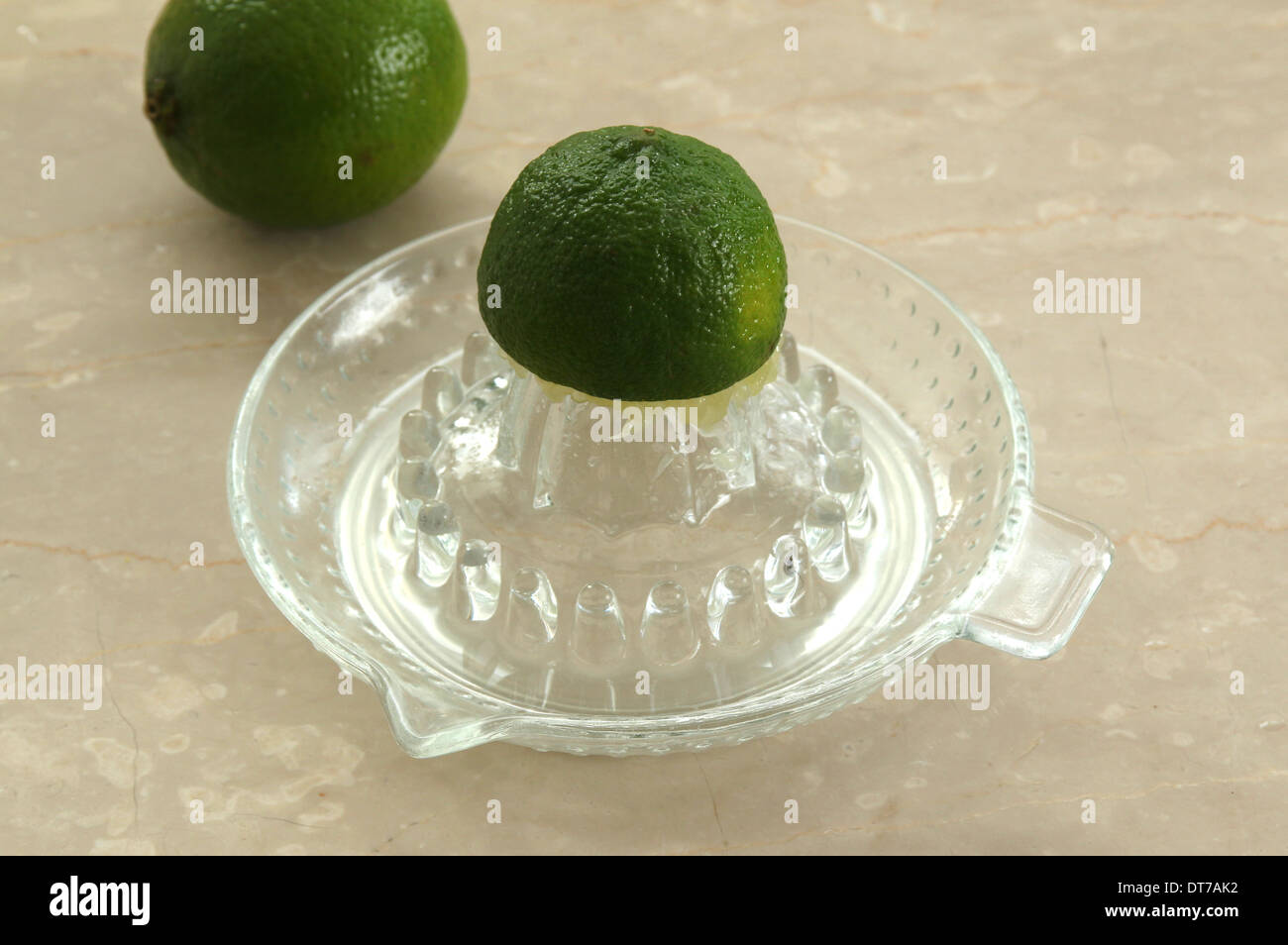 Sammeln von limettensaft oder auf ein Glas saftpresse Entsafter, auf einem cremefarbenen Marmor Hintergrund (4 von 5) Stockfoto