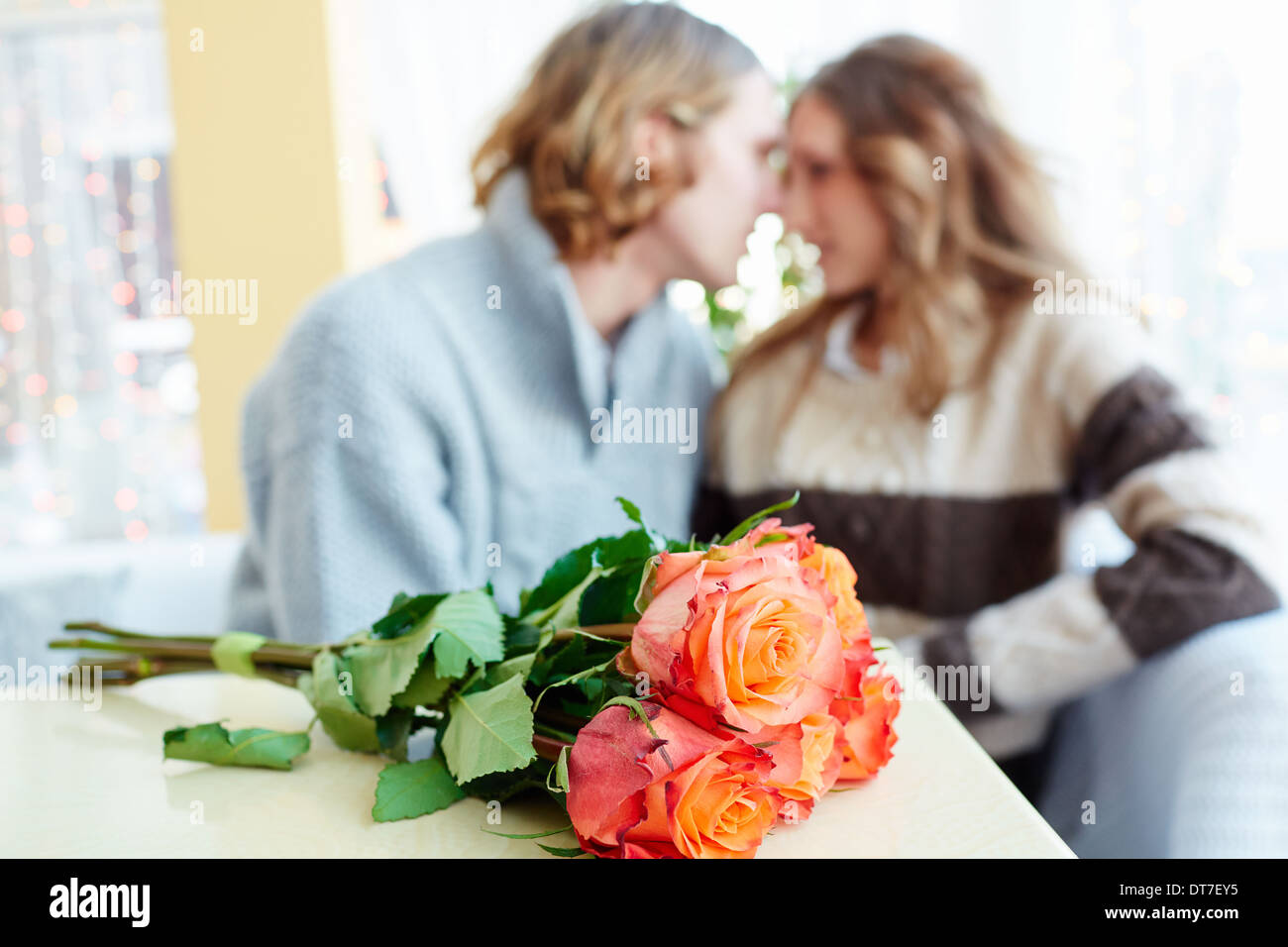 Ein Strauß roter Rosen auf Tisch und junge Liebhaber flirten im Hintergrund Stockfoto