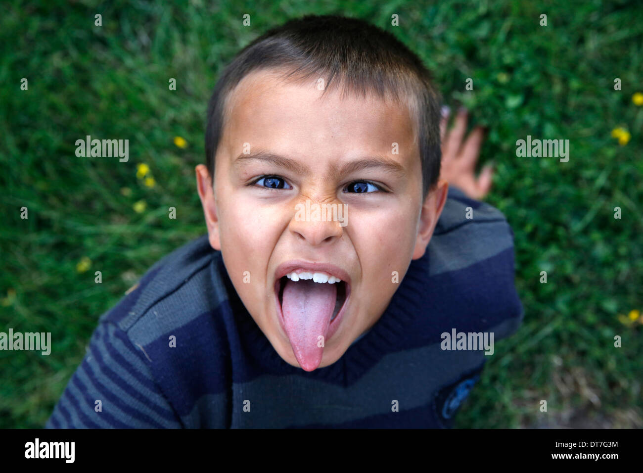 7-jähriger Junge seine Zunge ziehen Stockfoto