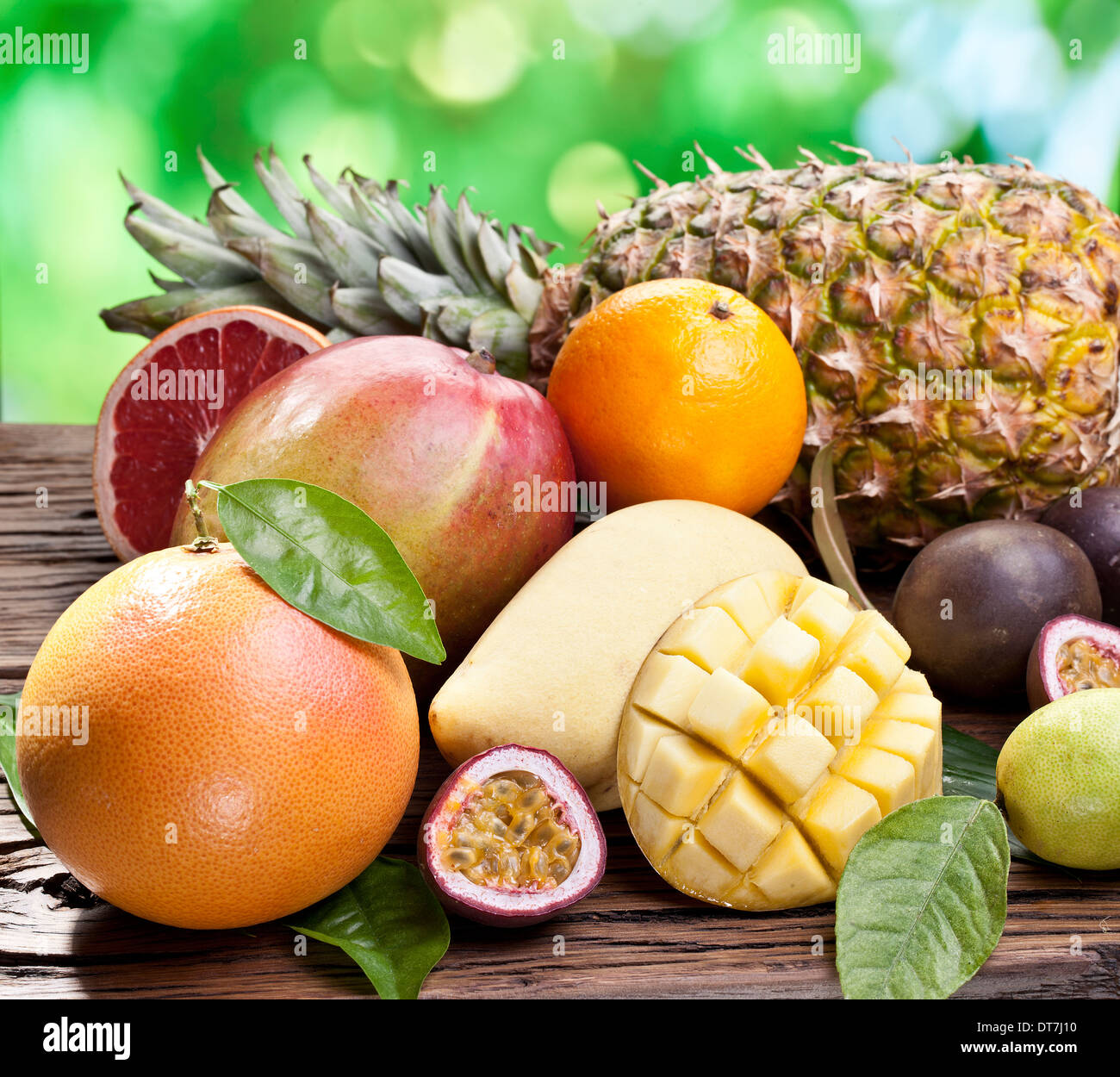 Exotische Früchte auf einem Holztisch mit dunkelgrünem Laub auf dem Hintergrund. Stockfoto