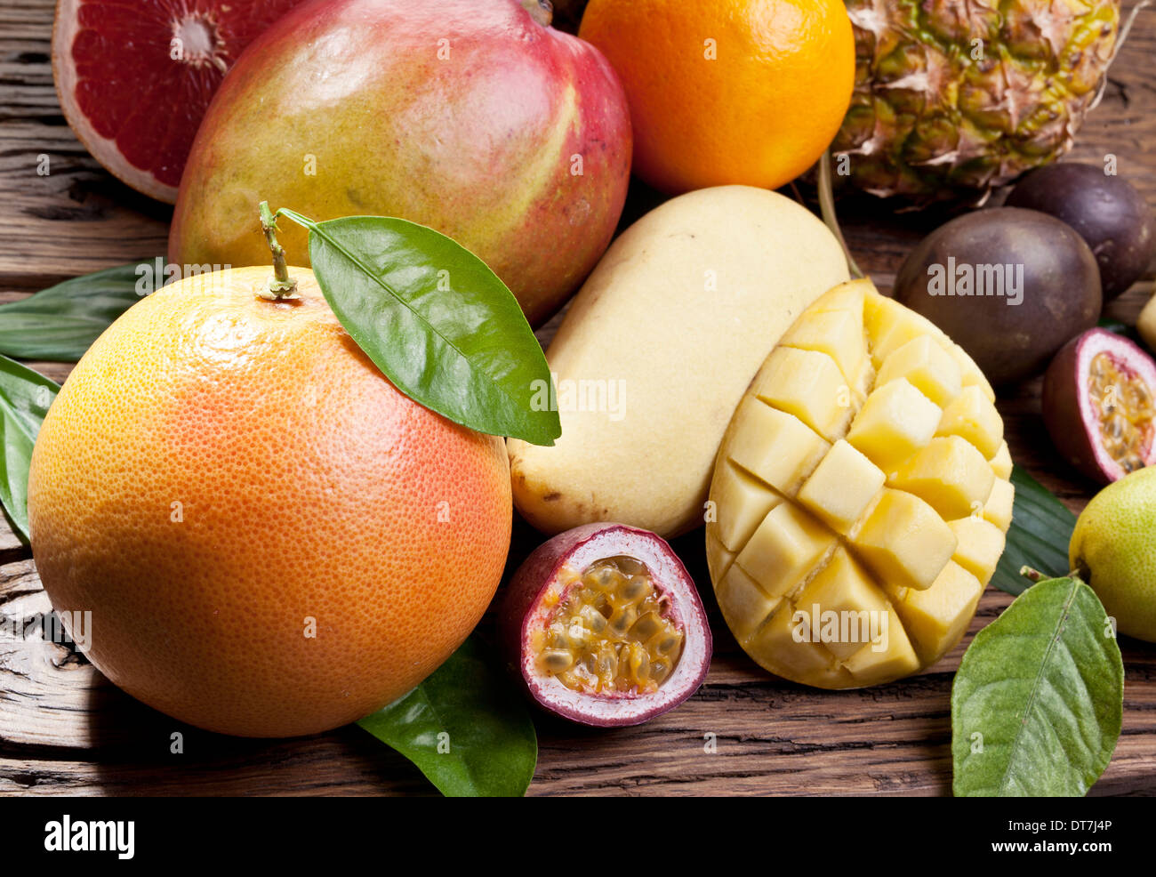 Exotische Früchte auf einem Holztisch mit dunkelgrünem Laub auf dem Hintergrund. Stockfoto