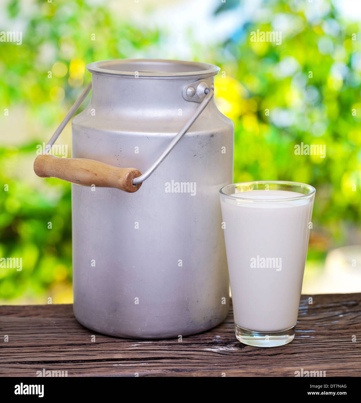 Milch in Aluminiumdose und Glas auf dem alten Holztisch im Freieneinstellung. Stockfoto