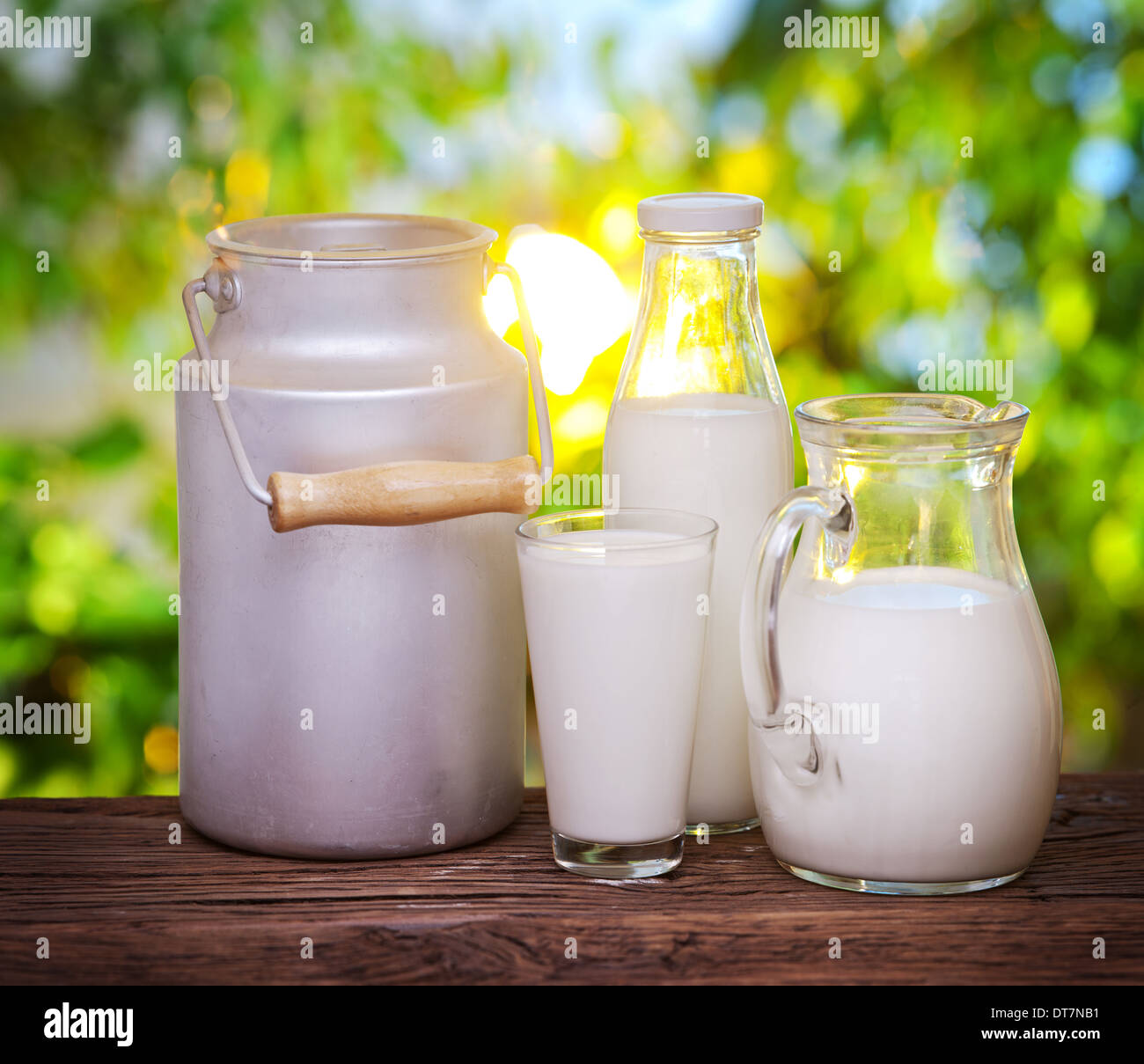 Milch in verschiedenen Gerichten auf dem alten Holztisch im Freien. Stockfoto