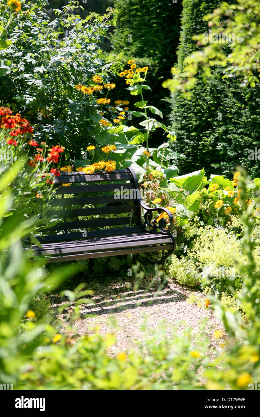 Einsame Gartenbank, umgeben von Pflanzen Stockfoto