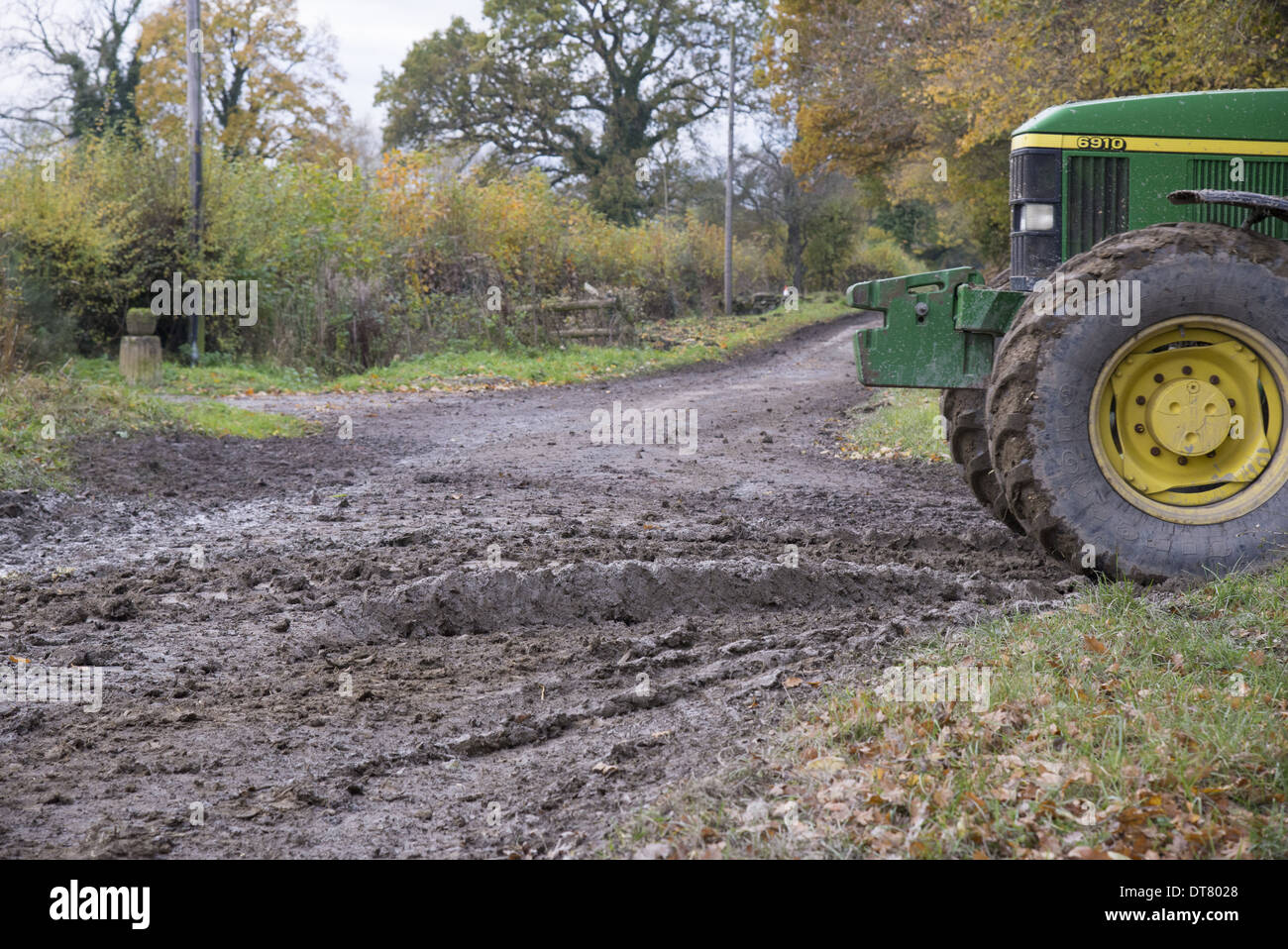 John Deere Traktor neben matschigen Landstraße, Welshpool, Powys, Wales, November Stockfoto